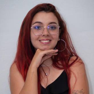 Uma mulher, com idade entre 20 e 25 anos, está olhando para a foto. Ela tem cabelo longo e ruivo